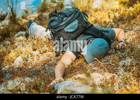 Young man tourist lying exhausted on ground and feeling bad. Danger accident concept. Stock Photo