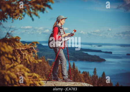 Young woman tourist with map standing on mountain top and looking aside Stock Photo