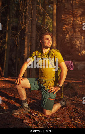 Young smiling man tourist in wild forest at sunset light Stock Photo