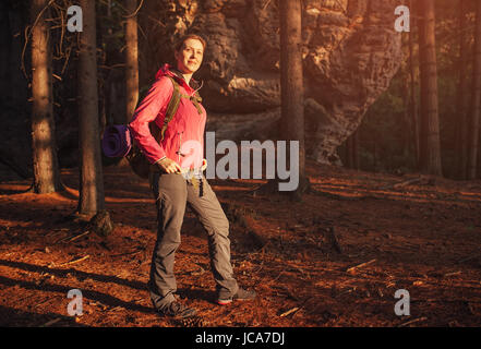 Young woman tourist standing in wild forest at sunset light Stock Photo
