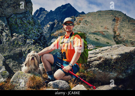 Young man tourist with dog portrait on high mountains background Stock Photo