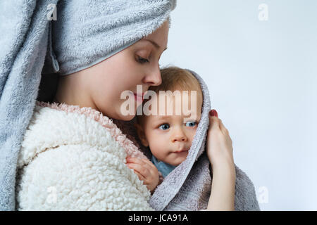 Young woman portrait with one year baby in bathrobe after washing and spa Stock Photo