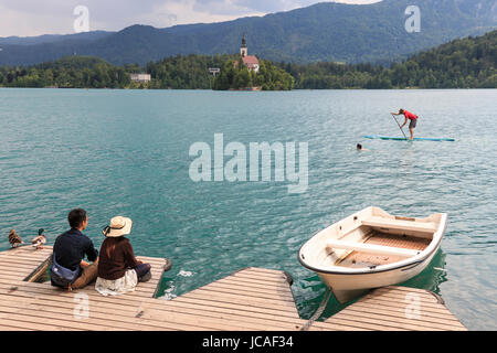 Bled, Slovenia - June 3, 2017: Tourists sitting on the bank of lake Bled. Stock Photo