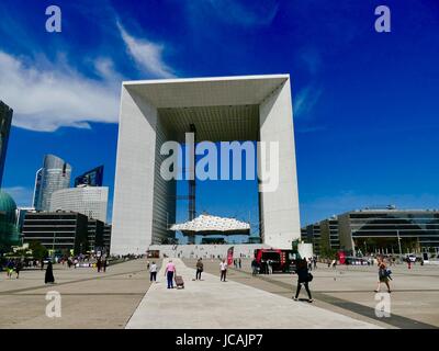 Grande Arche La Défense under bright blue skies and interesting clouds with many people walking about on June weekday. Metropolitan Paris, France Stock Photo