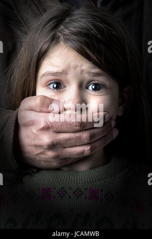 Scared young girl with an adult man's hand covering her mouth Stock Photo