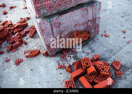 Stack of new silicate bricks in misted polyethylene with the piles of beaten bricks nearby. Stock Photo