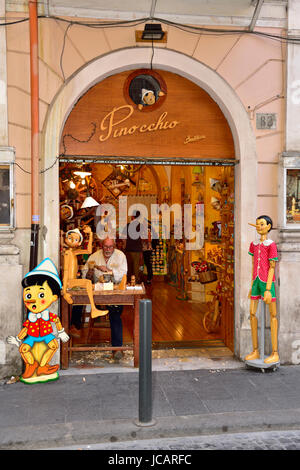 Shop selling Pinocchio souvenirs in Rome, Italy with man carving Pinocchio puppets Stock Photo