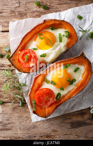 Healthy food: baked sweet potato with fried egg and tomato close-up on the table. vertical view from above