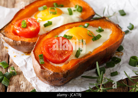 healthy baked sweet potato with fried egg and tomato close-up on the table. Horizontal Stock Photo
