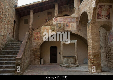 Pretty courtyard in the Palazzo del Popolo, with fresco fragments by Sodoma: San Gimignano, Tuscany, Italy Stock Photo
