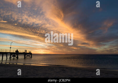 Sillouetted people fishing off the end of the Normanville Jetty, South Australia at sunset. This area is in the Fleurieu Peninsula. Stock Photo