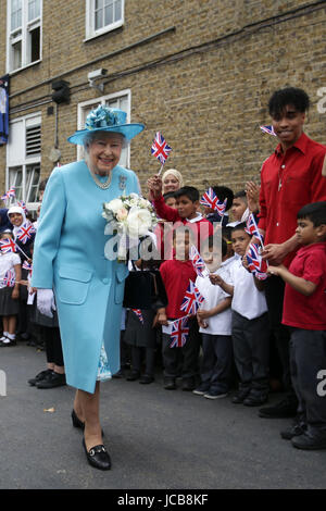 Queen Elizabeth II smiles as she walks past flag-waving school children after visiting Mayflower Primary School during a visit to Poplar in Tower Hamlets in East London, as part of commemorations to mark the centenary of the bombing of Upper North Street School during the First World War.