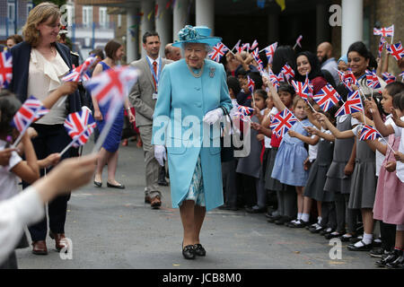 Queen Elizabeth II smiles as she walks past flag-waving school children after visiting Mayflower Primary School during a visit to Poplar in Tower Hamlets in East London, as part of commemorations to mark the centenary of the bombing of Upper North Street School during the First World War.