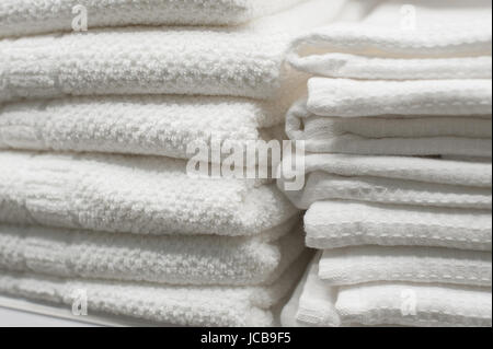 White towels stacked on a shelf in the closet. Stock Photo