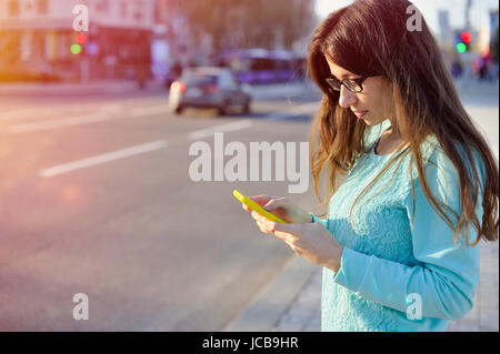 Beautiful young businesswoman written on smartphone in city Stock Photo