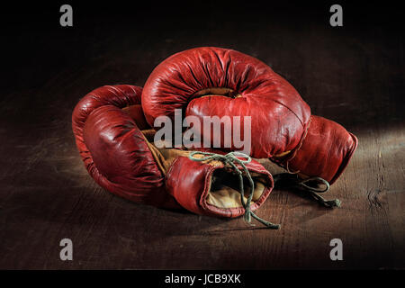 Old red boxing gloves on wooden background. Stock Photo
