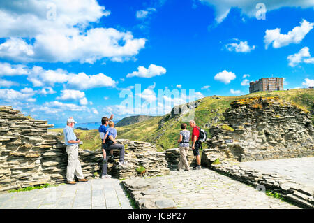 Tourists at the historic site of Tintagel Castle with Camelot Castle Hotel perched high on a cliff top, Cornwall, England, UK Stock Photo