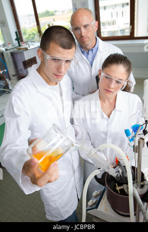 two student performing experiment in a laboratory under teacher surveillance Stock Photo