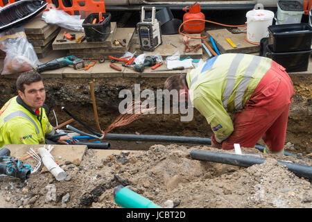 Technicians working in an excavation on electrical power cables being jointed after installation Stock Photo