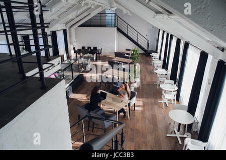 Two business partners sitting at the desk in office and interacting. Stock Photo