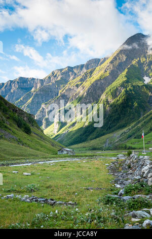 LES CHAPIEUX, FRANCE - AUGUST 27: Mountains chain with lonely chalet at the hill side. The region is a stage at the Mont Blanc tour, which crosses three countries. August 27, 2014 in Les Chapieux. Stock Photo