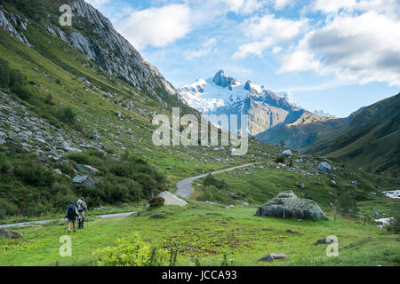 LES CHAPIEUX, FRANCE - AUGUST 27: Hikers walking with Glacier Needles in the background. The region is a stage at the Mont Blanc tour, which crosses three countries. August 27, 2014 in Les Chapieux. Stock Photo