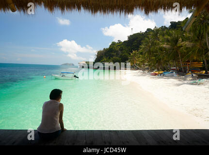 Silhouette women sit on wooden jetty with rooftop beside tropical sea in sunny day , Rawa island . Malaysia . Stock Photo