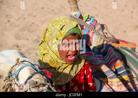 The young girl-cameleer from Bedouin village in Sahara desert with her camel, shouting inviting tourists, egypt hurghada Stock Photo