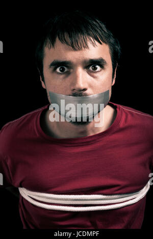 Kidnapped man hostage with tape over mouth and tied up with rope Stock Photo