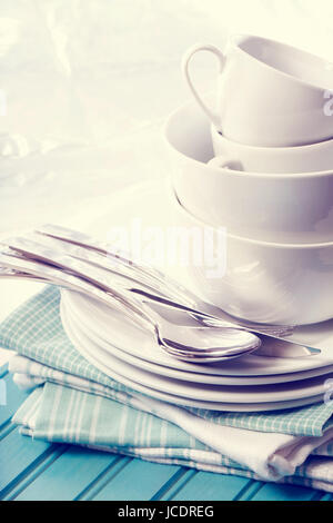 A stack of clean white plates and cups on blue napkins and wooden board Stock Photo
