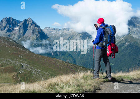 COL DE BALME, FRANCE - SEPTEMBER 01: Backpacker photographing view with Aiguille de Loriaz in the background. The area is a stage of the popular Mont Blanc tour. September 01, 2014 in Col de Balme. Stock Photo