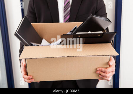 Portrait of young businessman holding cardboard in office Stock Photo