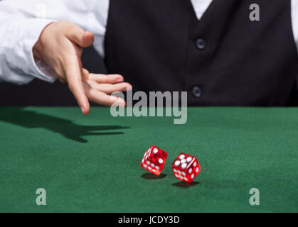 Croupier throwing a pair of red dice across the green felt on a card table in a casino in a game of chance Stock Photo