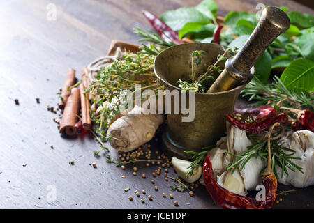 Different herbs and spices on a wooden table . Old copper mortar with spices . Stock Photo