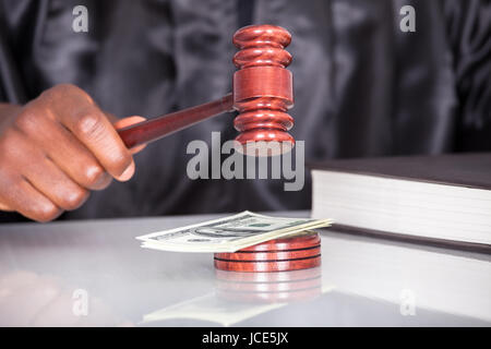 Male Judge Striking The Gavel Dollar Note In A Courtroom Stock Photo