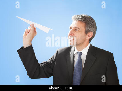 Portrait of successful senior businessman launching a paper plane Stock Photo