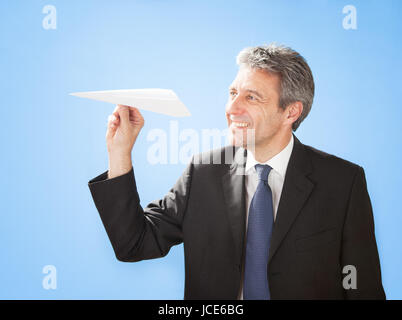 Portrait of successful senior businessman launching a paper plane Stock Photo