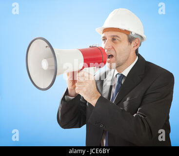 Portrait of senior architect shouting into megaphone on sky Stock Photo
