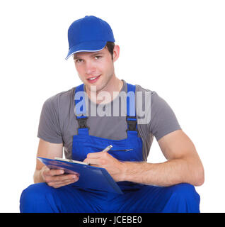 Young Construction Worker Writing On Clipboard Over White Background Stock Photo