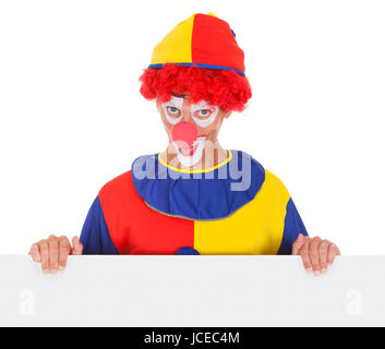 Portrait Of A Happy Joker Holding Blank Placard Over White Background Stock Photo