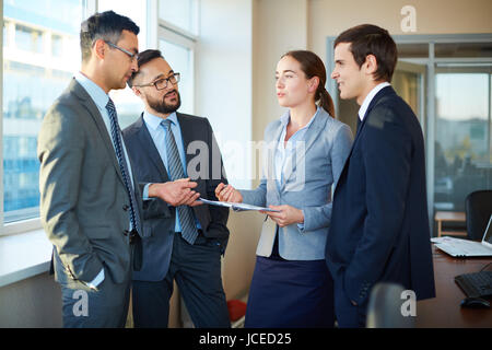 Group of colleagues discussing documents and business plans in office Stock Photo