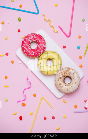 Party. Different colourful sugary round glazed donuts and bottles of drinks on pink background. Stock Photo