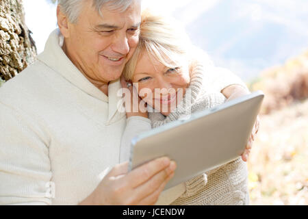 Senior couple using tablet in forest Stock Photo
