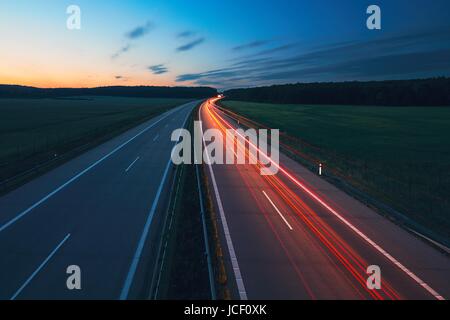 Tail lights of the cars during sunrise on the highway.   Transportation and cars theme. Stock Photo