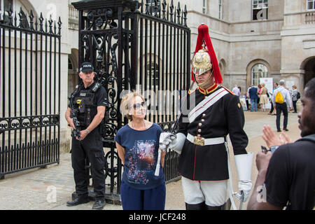 London, UK. 14th June, 2017. A tourist poses next to a footguard, sword drawn, from the Household cavalry, Blues and Royals at the entrance to Horseguards Parade on Whitehall. In the background an armed police officer watches on. Credit: David Rowe/Alamy Live News Stock Photo