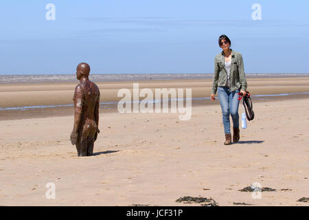 Crosby Beach, Merseyside, UK. UK Weather. 15th June, 2017. Sunny day in the North-west as shipping enters and leaves the Mersey estuary. 100 iron men by the sea at ‘Another Place’ sculptures by Antony Gormey. on Crosby Beach, where one of the sculptures, looking out to sea, has adopted a blue and orange artwork decoration. Skies arew expected to brighten through the day making for a dry but fresher afternoon. Credit; MediaWorldImages/AlamyLiveNews Stock Photo