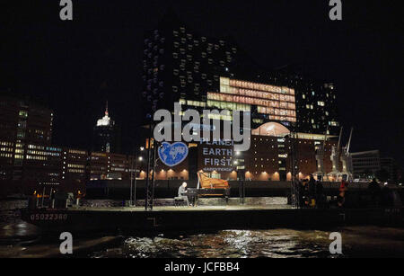 Hamburg, Germany. 16th June, 2017. Greenpeace activists project a heart-shaped earth with the demand 'Planet Earth First' on to the Elbphilharmonie (Elbe Philharmonic Hall) in Hamburg, Germany, 16 June 2017. At the same time Rumanian-Israeli pianist Michael Abramovich played Frédéric Chopins Nocturne op. 9, Nr. 2 in E flat major on a concert grand on the Elbe River. Photo: Georg Wendt/dpa/Alamy Live News Stock Photo