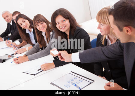 Businessman Handing Out A Business Card To A Businesswoman In Meeting Stock Photo