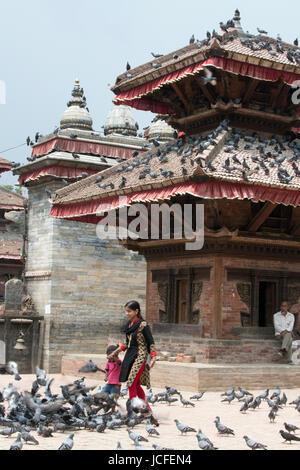 Woman and child feeding pigeons outside the Jagannath Temple, Kathmandu Durbar Square Nepal Stock Photo