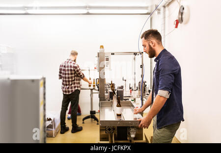 men with bottles on conveyor at craft beer brewery Stock Photo